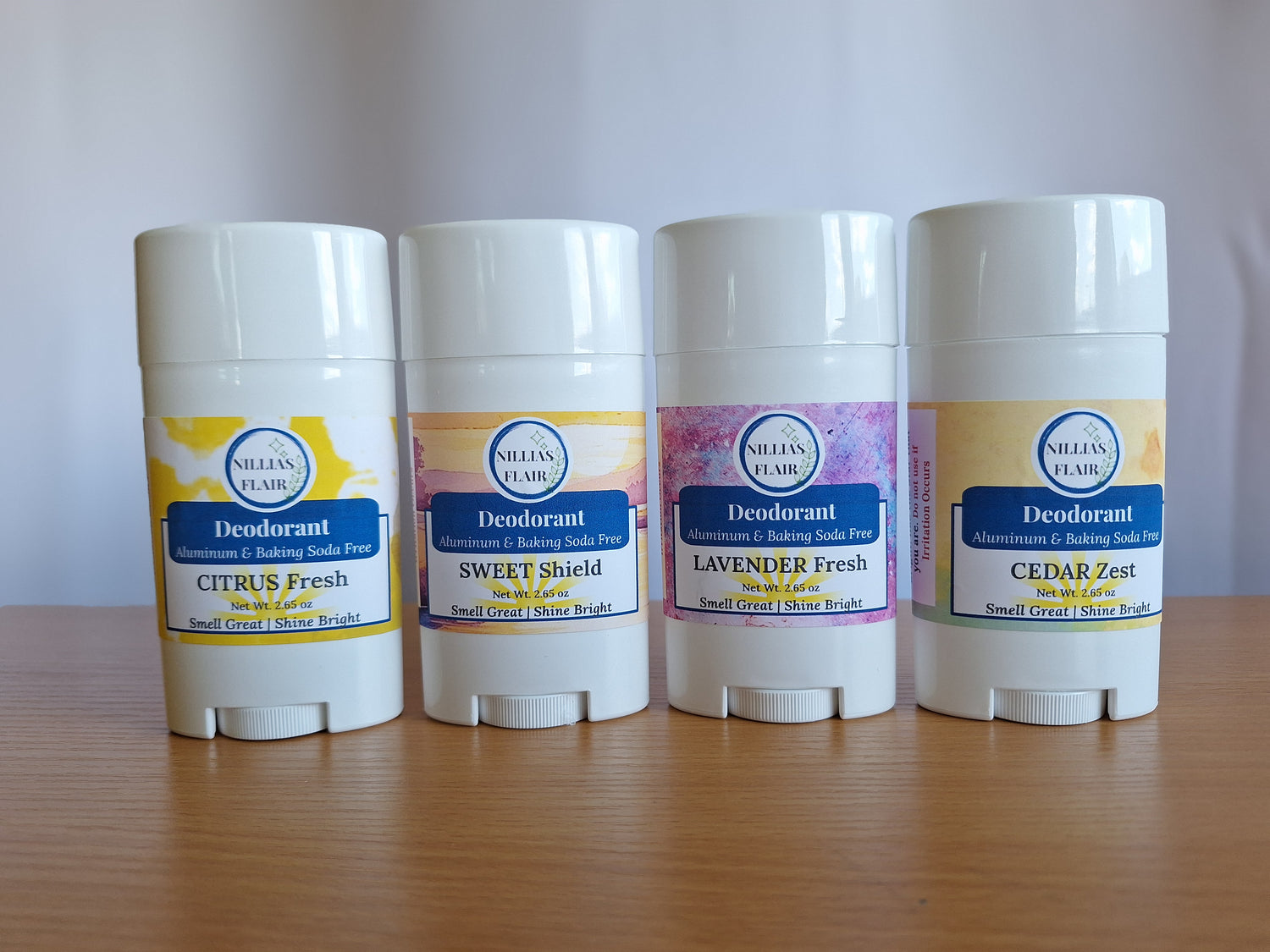 Four deodorant sticks with different scents on a wooden surface.